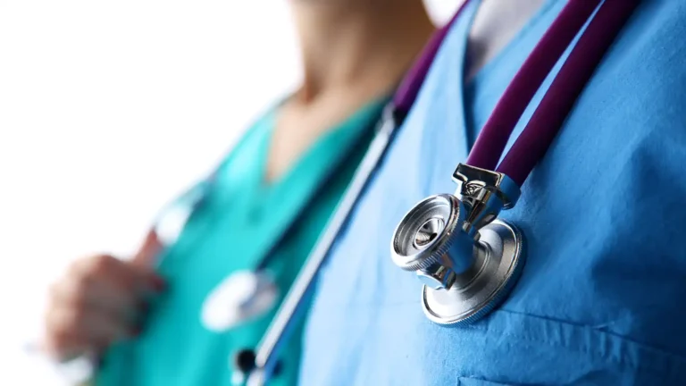two doctors standing with stethoscopes; one in blue scrubs one in green scrubs
